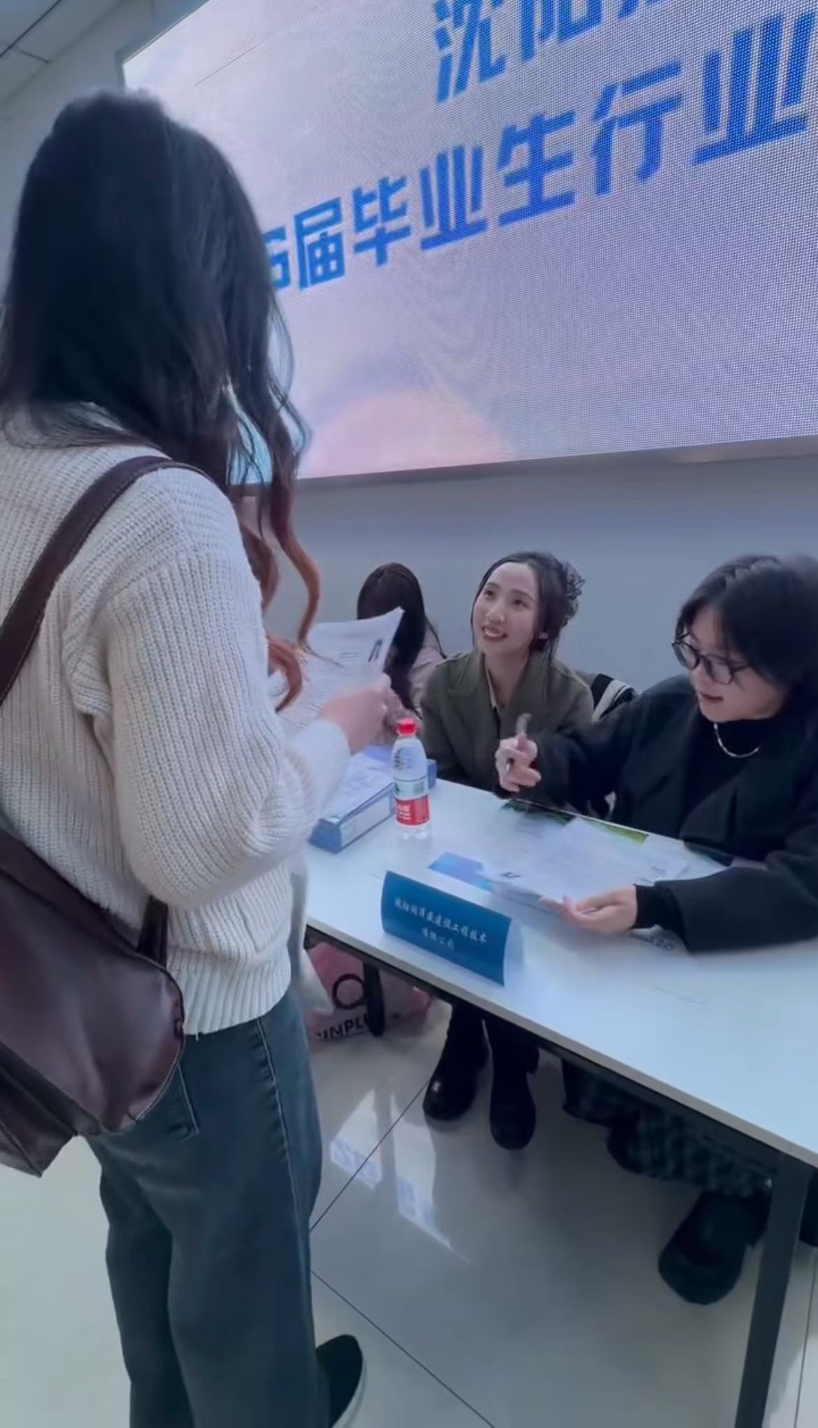 校园招聘会现场,工作人员与应聘学生沟通